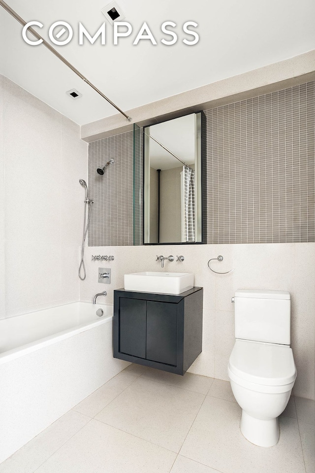 full bathroom with toilet, tile patterned flooring, shower / bath combo with shower curtain, vanity, and tile walls