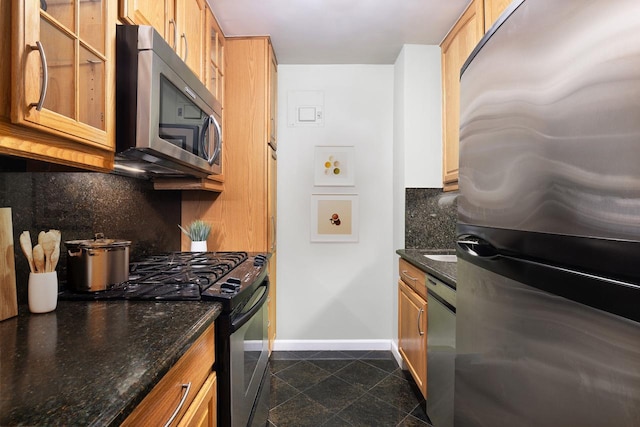 kitchen featuring decorative backsplash, baseboards, dark stone counters, granite finish floor, and stainless steel appliances