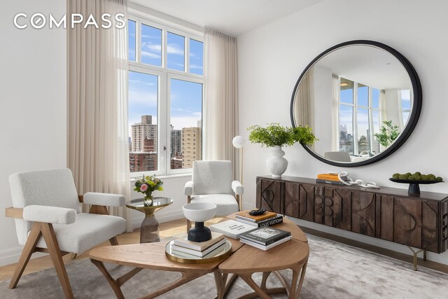 sitting room featuring baseboards, a city view, and wood finished floors