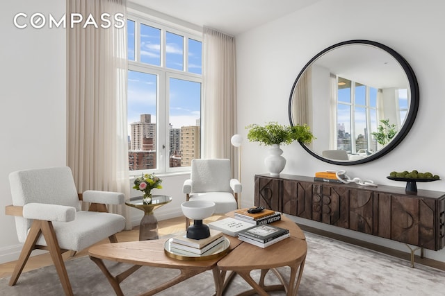 living area with a city view, baseboards, and wood finished floors