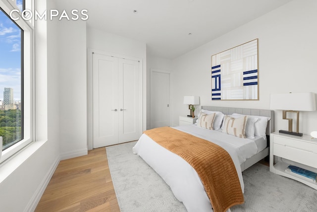 bedroom with a closet, baseboards, and light wood-style floors