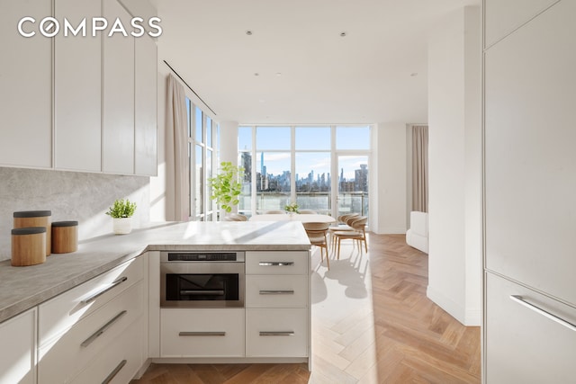 kitchen featuring a view of city, light countertops, oven, and white cabinetry