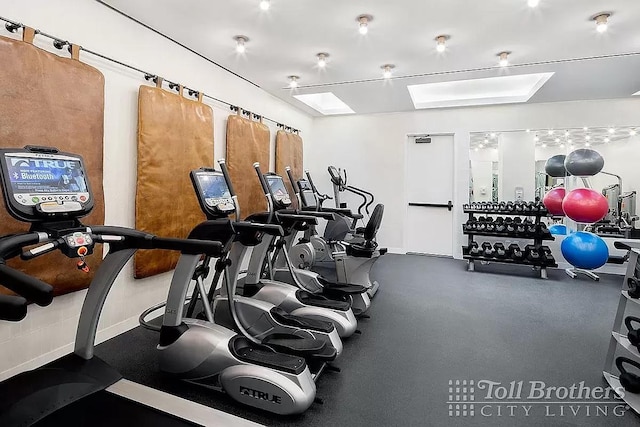 gym featuring a skylight and baseboards