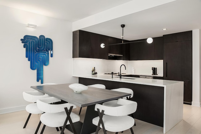 kitchen featuring light countertops, modern cabinets, a peninsula, and a sink