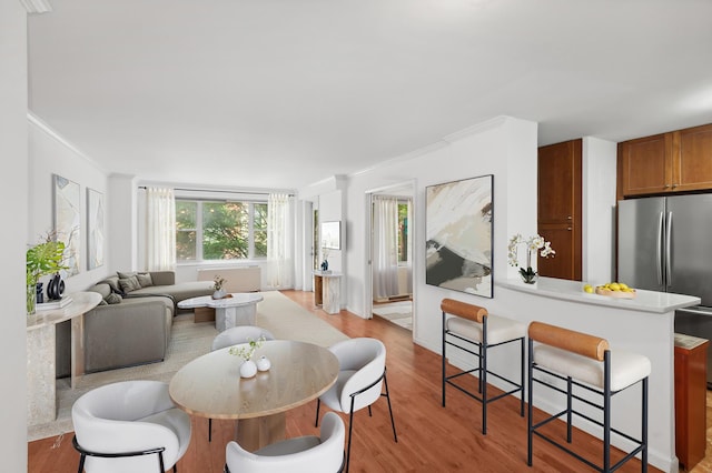 dining space with ornamental molding and light wood-style floors