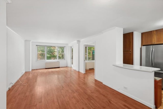 unfurnished living room with ornamental molding, light wood finished floors, and a wealth of natural light