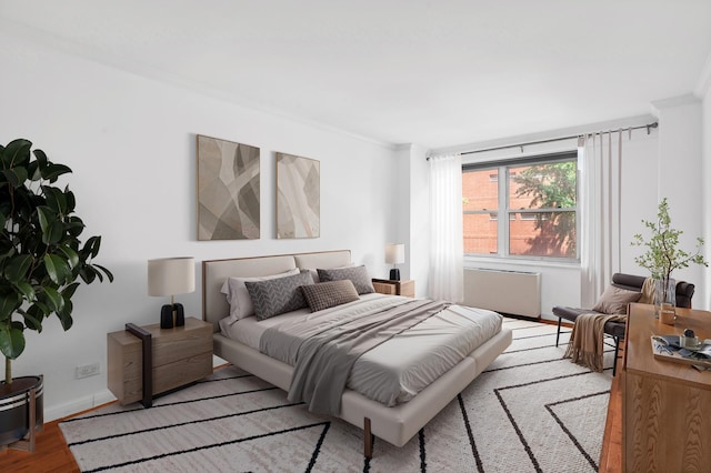 bedroom featuring baseboards, ornamental molding, and wood finished floors