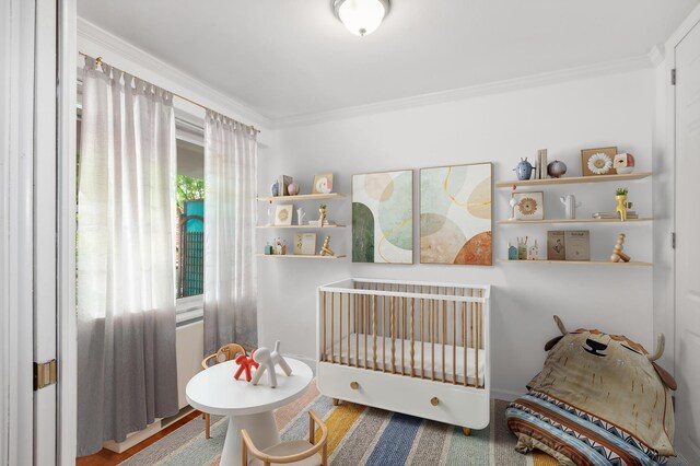 bedroom featuring a nursery area and crown molding