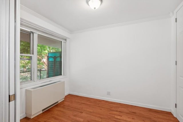 unfurnished room featuring ornamental molding, light wood-type flooring, radiator, and baseboards