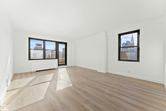 spare room with plenty of natural light, radiator heating unit, baseboards, and light wood-style floors