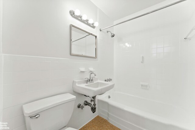 full bathroom featuring tile walls, bathtub / shower combination, toilet, a sink, and tile patterned floors