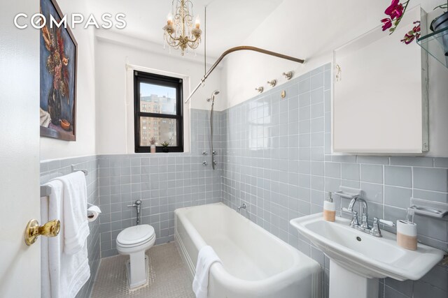 bathroom featuring tile walls, toilet, tub / shower combination, a sink, and tile patterned flooring