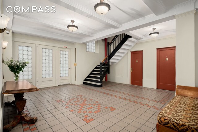 tiled entryway featuring ornamental molding, beam ceiling, and stairs