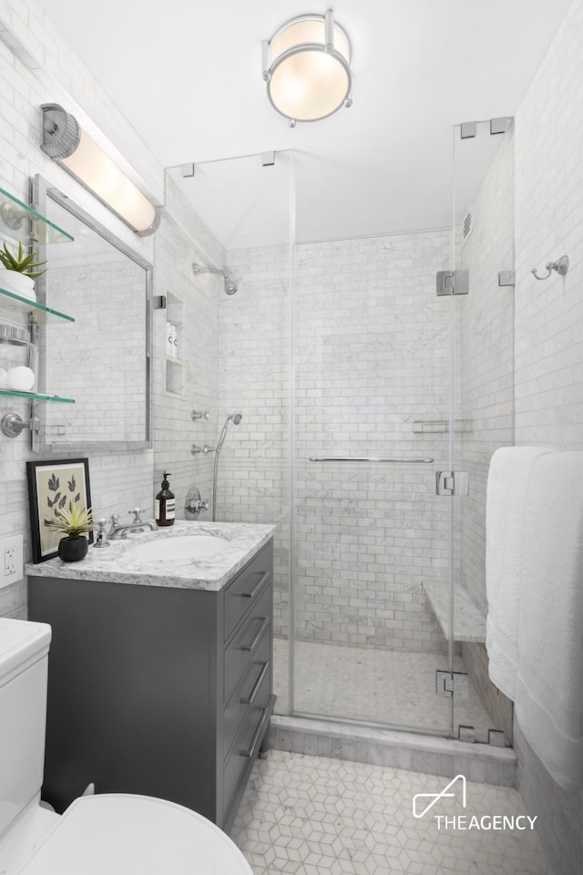 full bath featuring toilet, vanity, a stall shower, and tile patterned floors