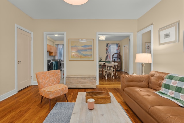 living area featuring washer and clothes dryer, baseboards, and wood finished floors