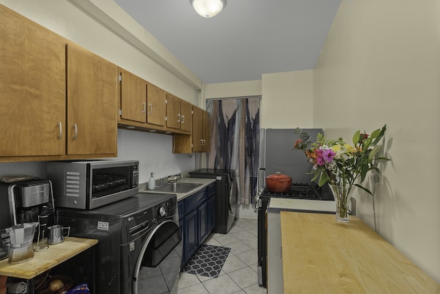 clothes washing area featuring light tile patterned floors, laundry area, washer / clothes dryer, and a sink