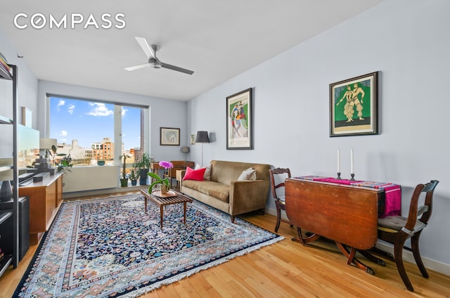 living room featuring ceiling fan, baseboards, and light wood-style flooring