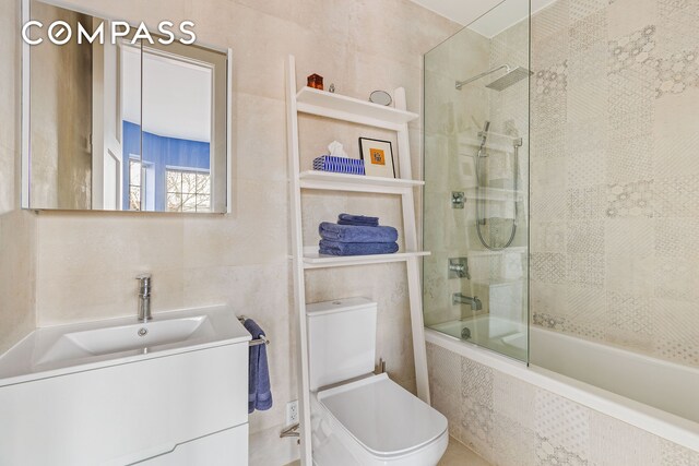 bathroom with tiled shower / bath, toilet, tile walls, and vanity