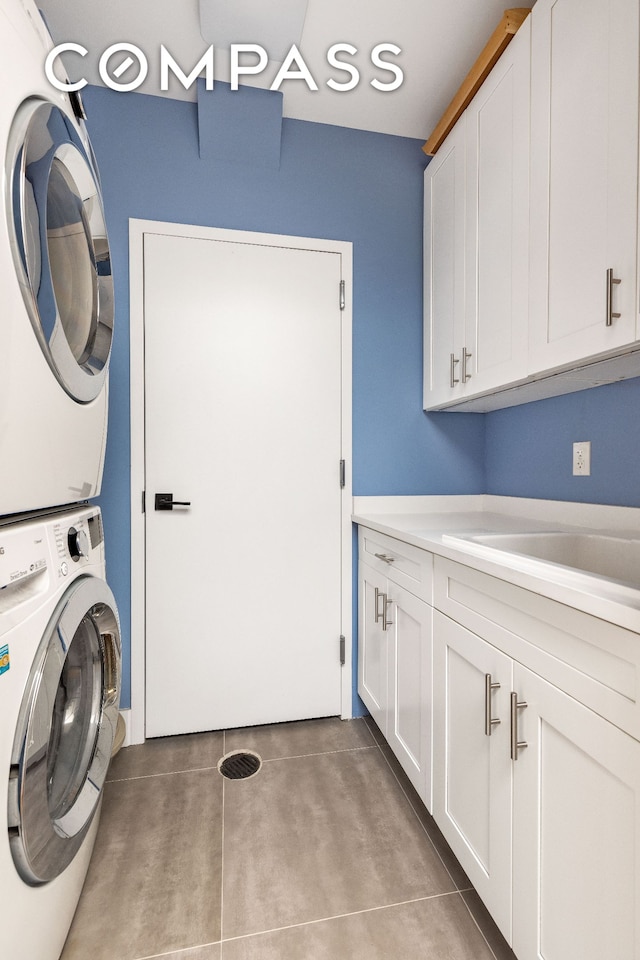 washroom with tile patterned flooring, a sink, cabinet space, and stacked washing maching and dryer