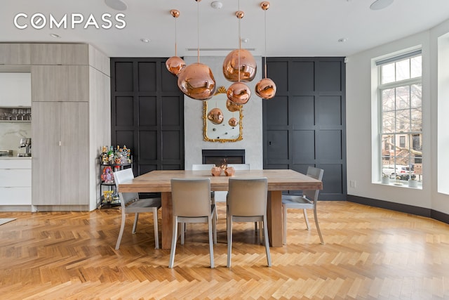 dining area featuring a fireplace, a decorative wall, and baseboards