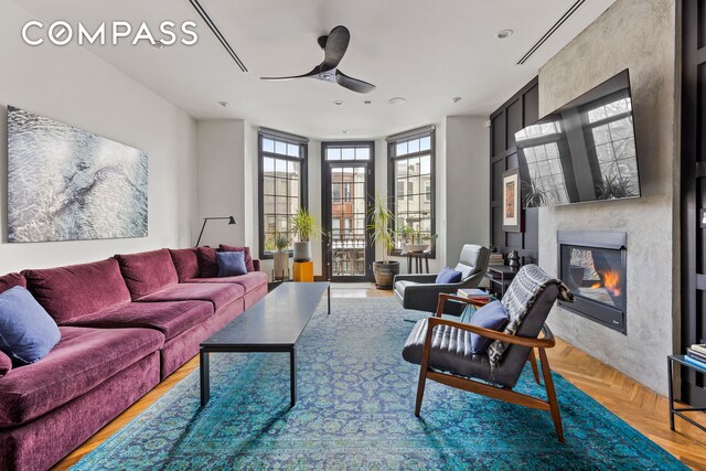 living room featuring a glass covered fireplace and ceiling fan