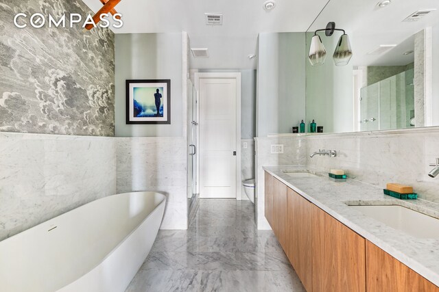 bathroom featuring a freestanding bath, visible vents, marble finish floor, and a sink