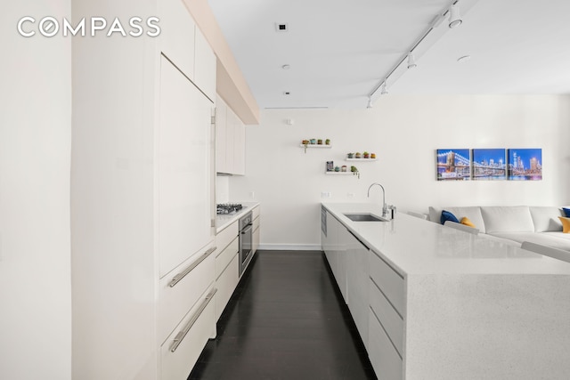 kitchen featuring modern cabinets, appliances with stainless steel finishes, a peninsula, white cabinetry, and a sink