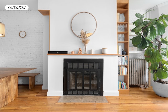 details featuring a fireplace with flush hearth, radiator, and wood finished floors