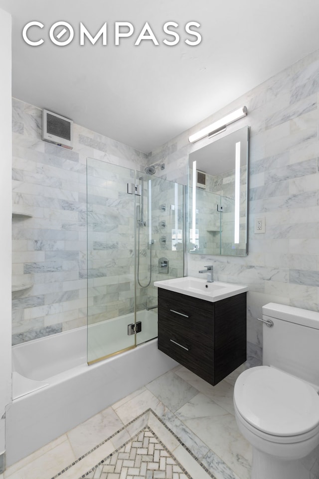 full bath featuring toilet, vanity, combined bath / shower with glass door, marble finish floor, and tile walls