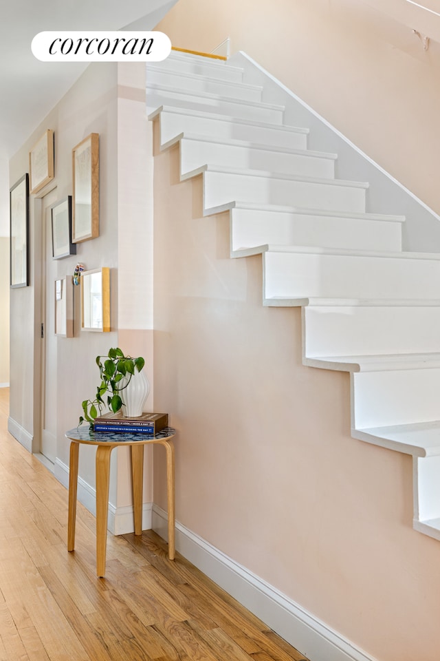 staircase featuring wood finished floors and baseboards