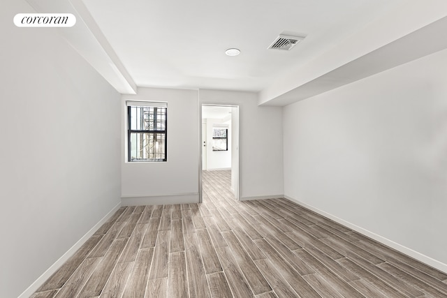 spare room with visible vents, baseboards, and wood finished floors