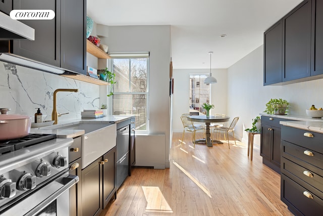 kitchen with decorative backsplash, stainless steel stove, light wood finished floors, and light stone countertops