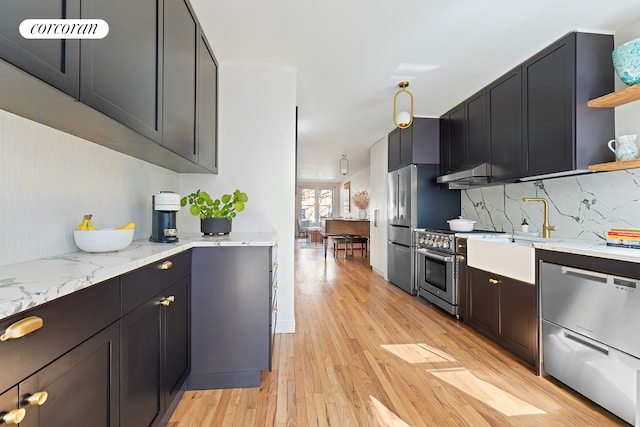 kitchen with decorative backsplash, light wood-style flooring, appliances with stainless steel finishes, light stone counters, and open shelves