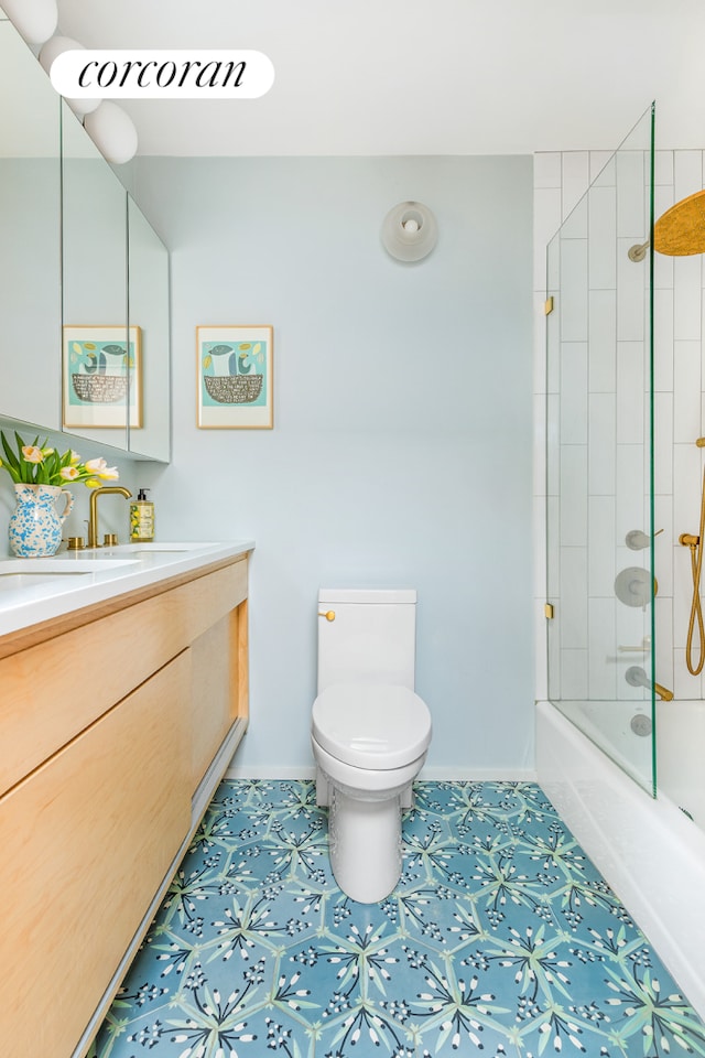 bathroom featuring enclosed tub / shower combo, vanity, toilet, and baseboards