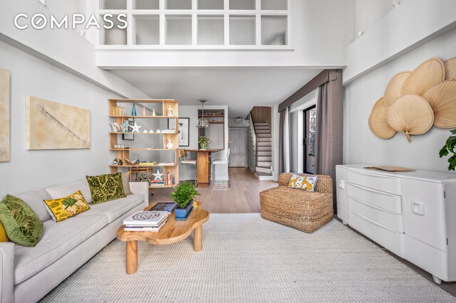 living room with stairs, a towering ceiling, and wood finished floors