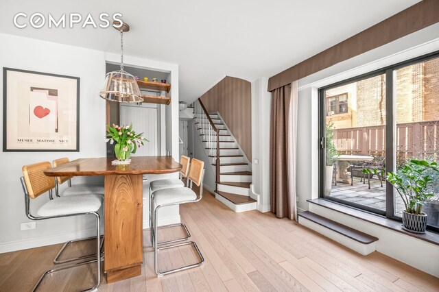 dining area with light wood finished floors, stairs, and baseboards