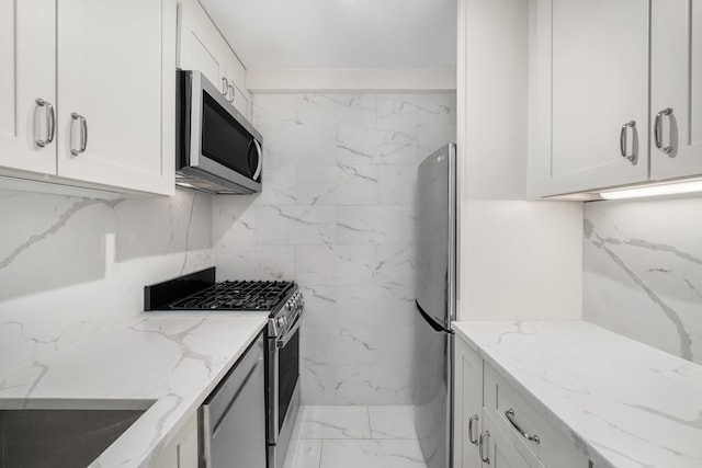 111 3rd Ave Unit 8K, New York City, NY 10003 - kitchen featuring appliances with stainless steel finishes, marble look tiles, light stone countertops, white cabinets, and a sink