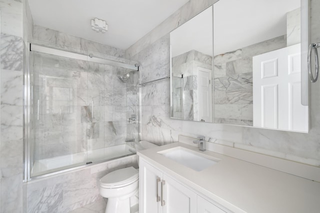 full bathroom with vanity, tile walls, toilet, and combined bath / shower with glass door