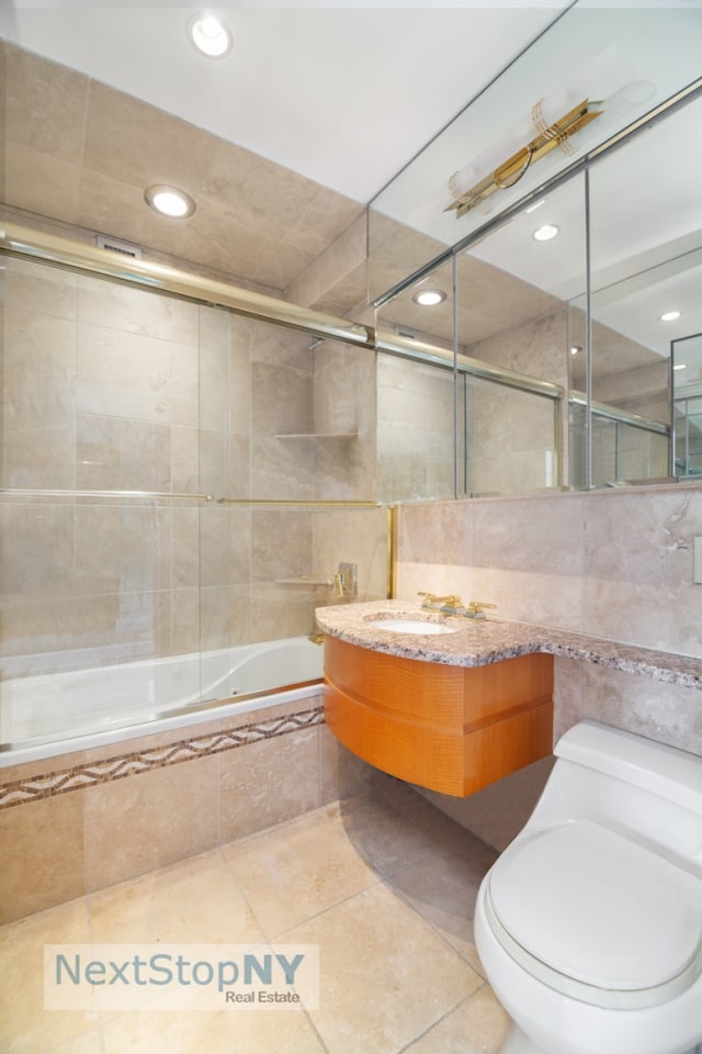 bathroom featuring tiled shower / bath combo, toilet, tile walls, and tile patterned floors