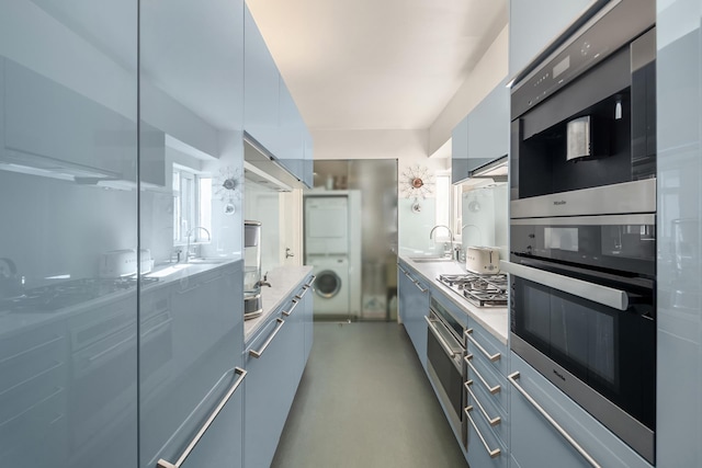 kitchen with stainless steel appliances, a sink, light countertops, modern cabinets, and washer / dryer