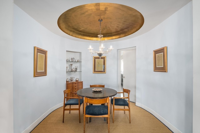 dining area with an inviting chandelier, baseboards, and a tray ceiling