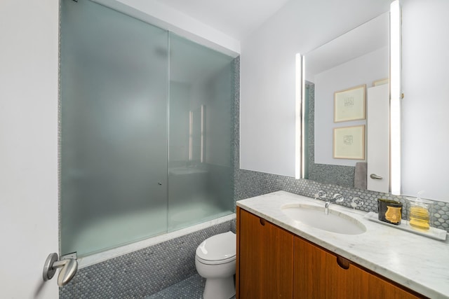 bathroom with backsplash, shower / bath combination with glass door, vanity, and toilet