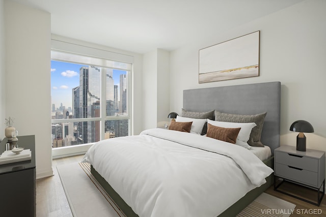 bedroom featuring a view of city and wood finished floors