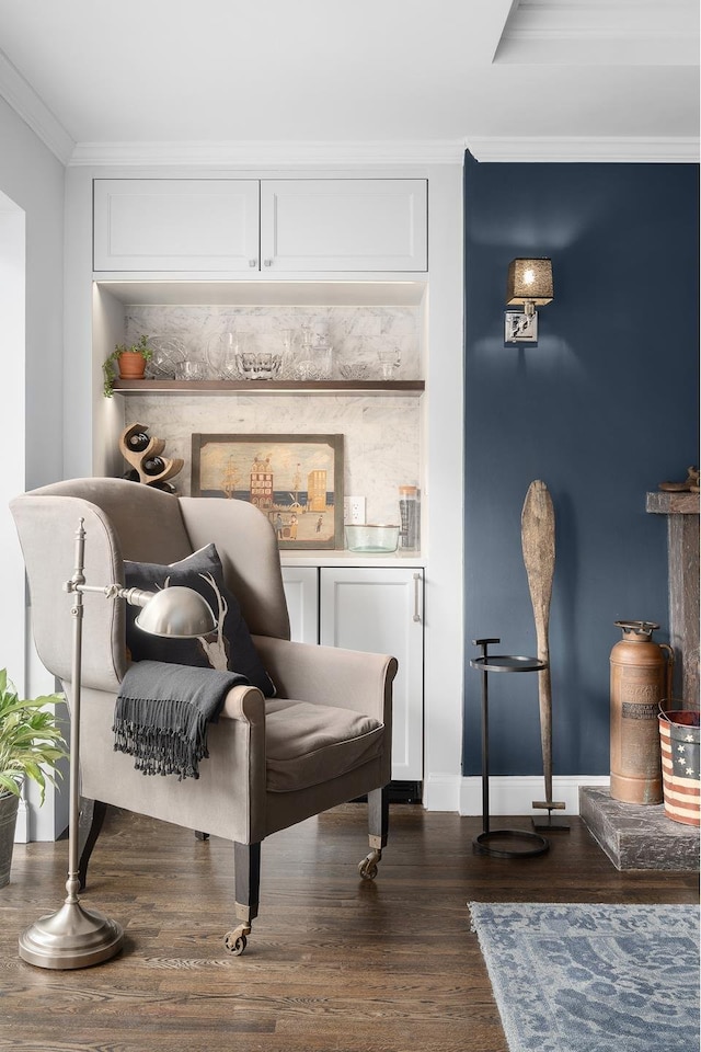 sitting room featuring baseboards, ornamental molding, and dark wood-type flooring