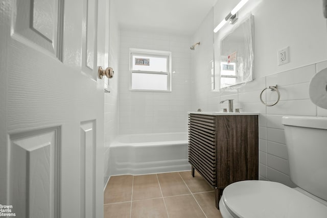 bathroom with tile walls, shower / bathtub combination, toilet, vanity, and tile patterned floors