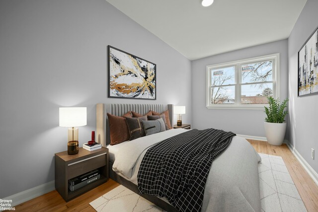 bedroom featuring light wood-type flooring, vaulted ceiling, and baseboards