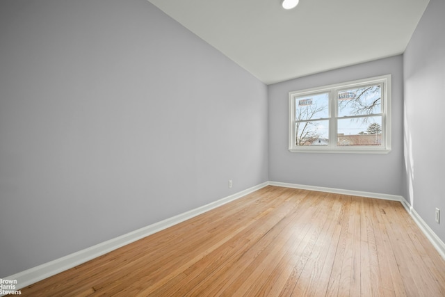 unfurnished room featuring lofted ceiling, light wood-style flooring, and baseboards