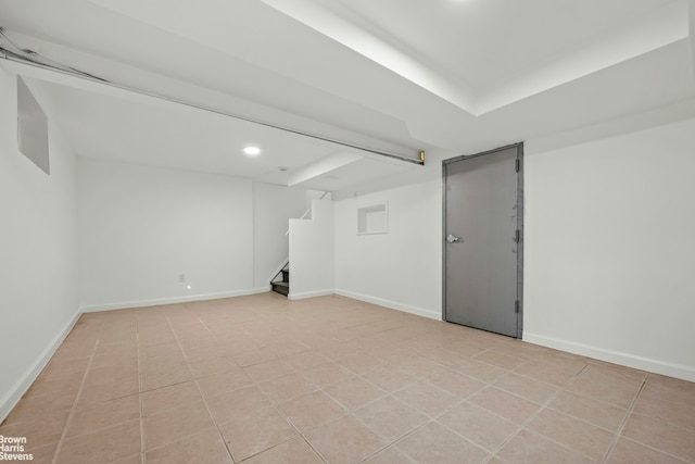 finished below grade area featuring light tile patterned floors, baseboards, and stairs