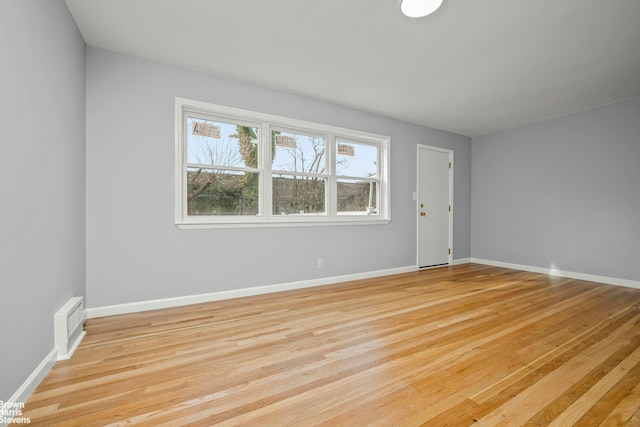 unfurnished room with light wood-style floors, visible vents, and baseboards