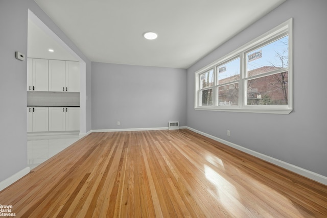 unfurnished living room featuring visible vents, light wood-style flooring, and baseboards